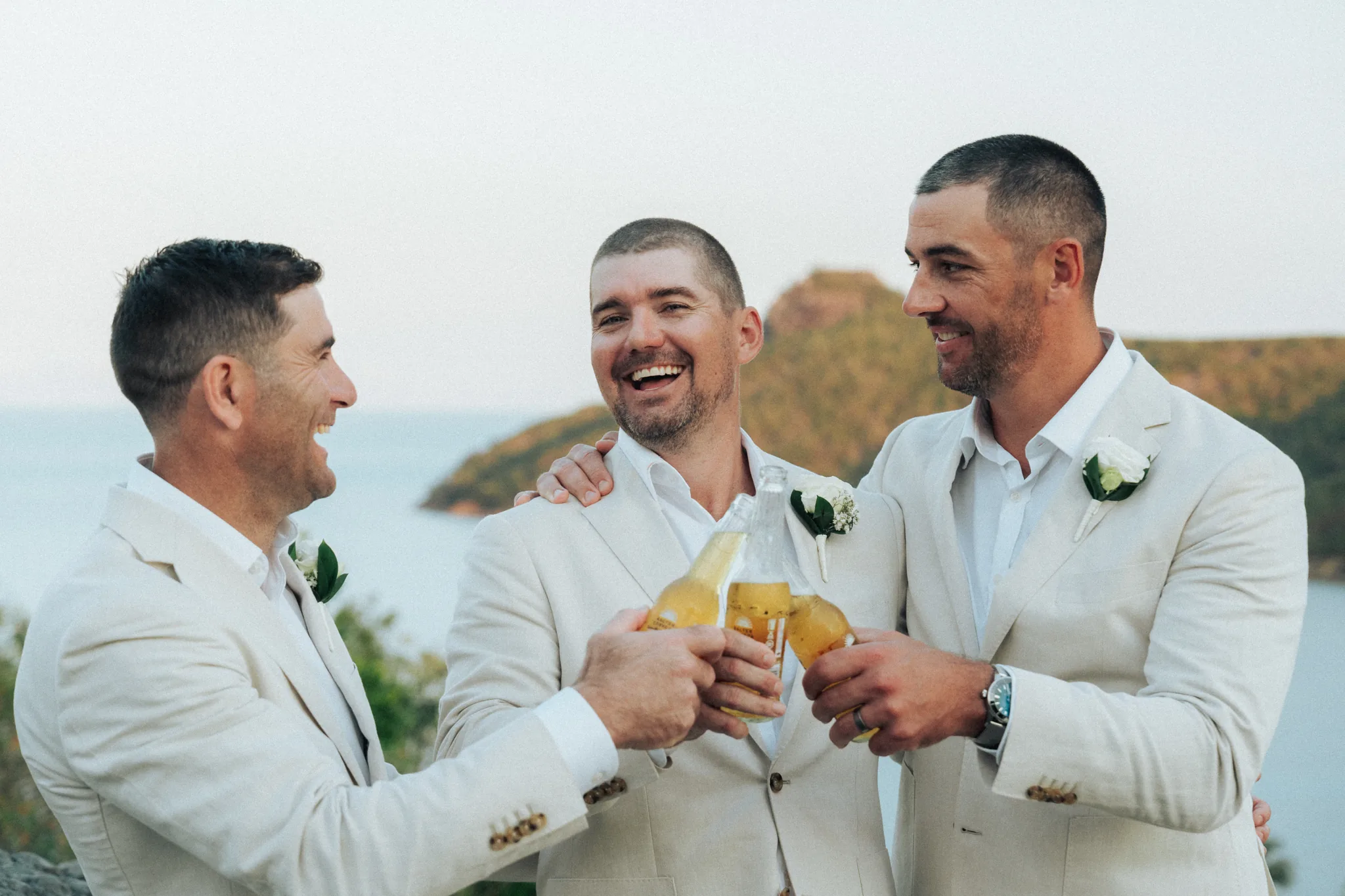 The groom and his groomsmen raise a champagne toast by the water