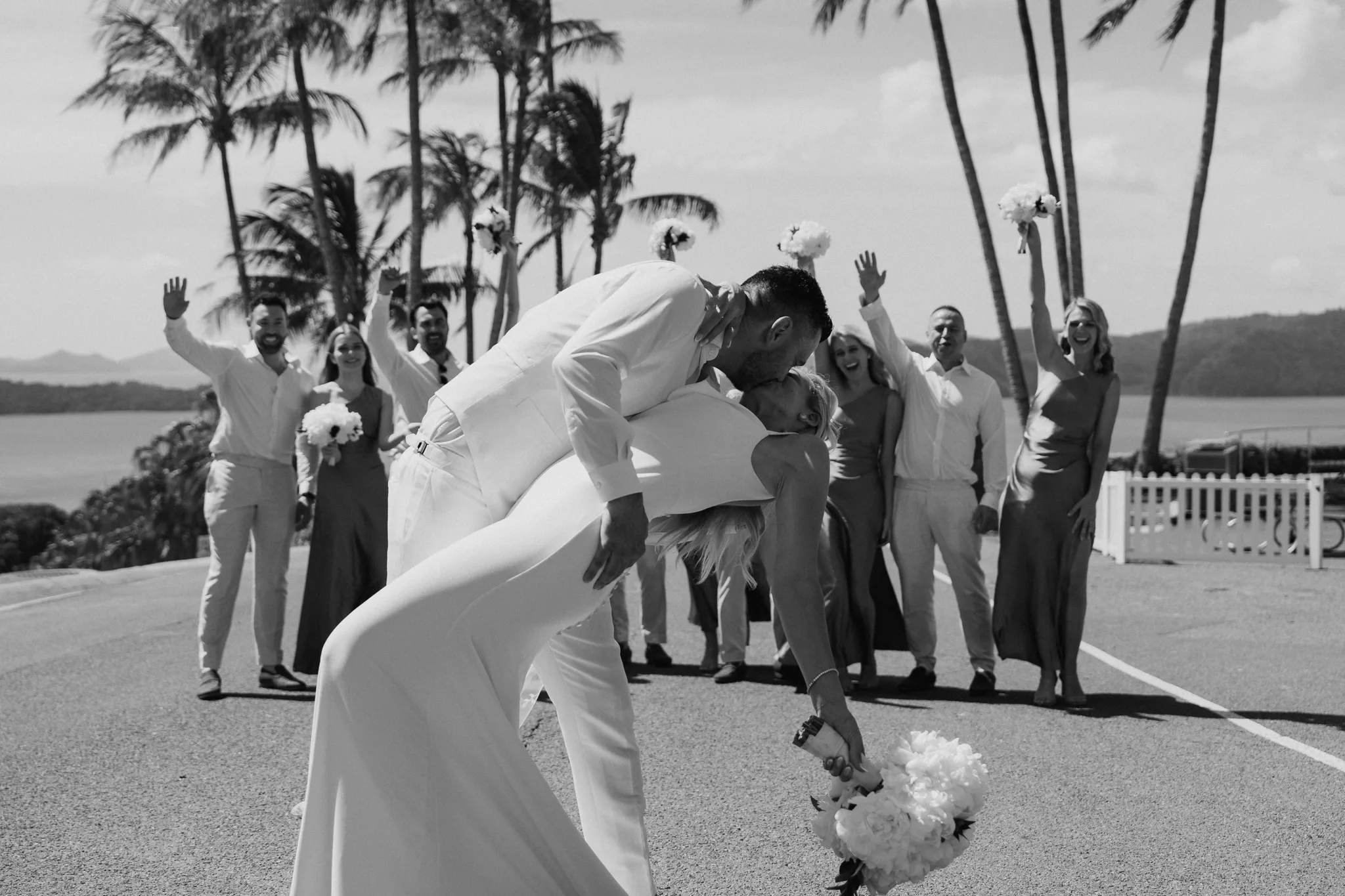 The bride's veil swirls as the couple turns together, in black and white