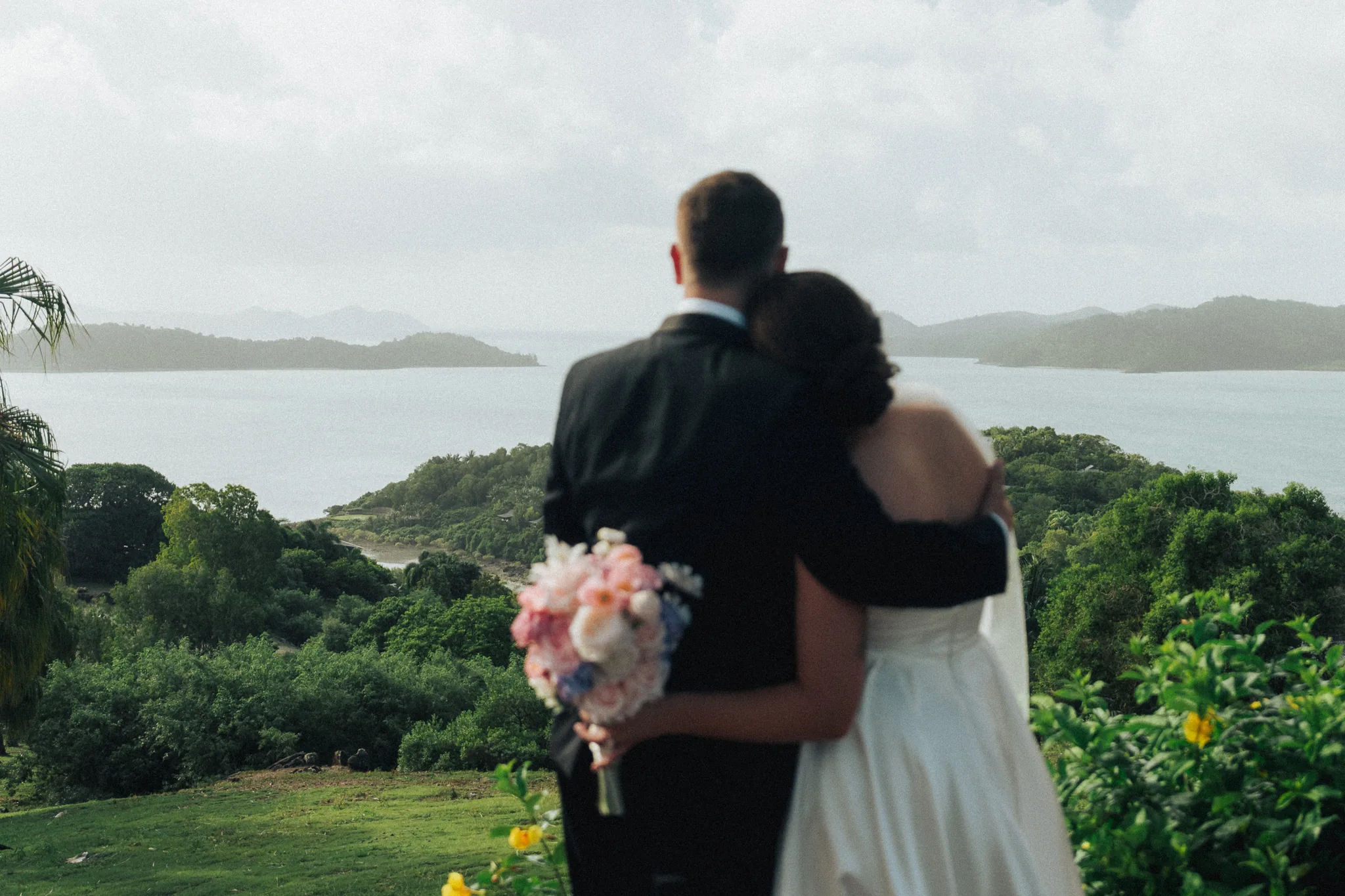 The couple embraces on a deck overlooking the bay